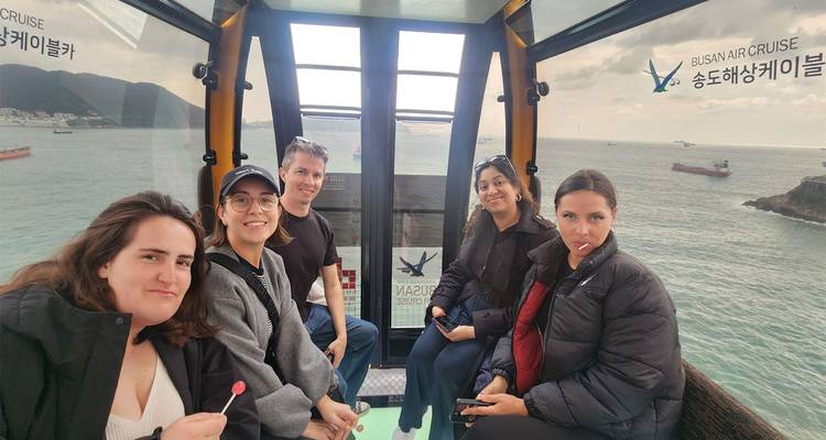 Friends enjoy views from inside the glass-floored Busan Air Cruise cable car.