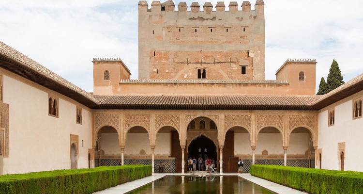 Palais avec des colonnes ornées et un bassin réfléchissant.
