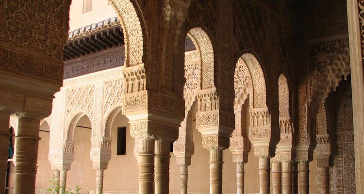 Arcos moriscos y estuco intrincado del interior del palacio de la Alhambra de Granada bañado en luz cálida
