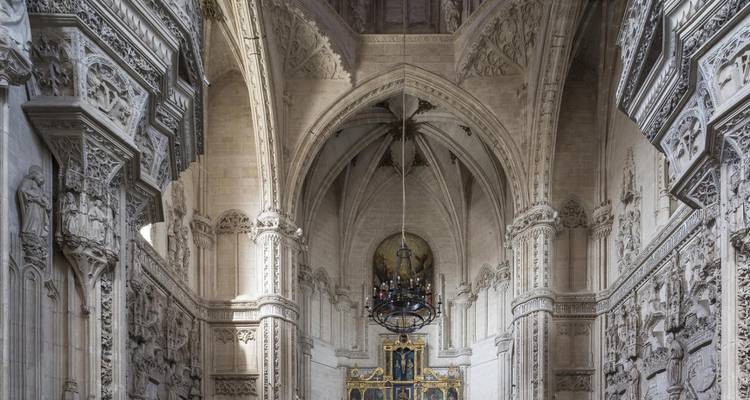 Interior gótico de un monasterio español con bóvedas de piedra elevadas y relieves ornamentados