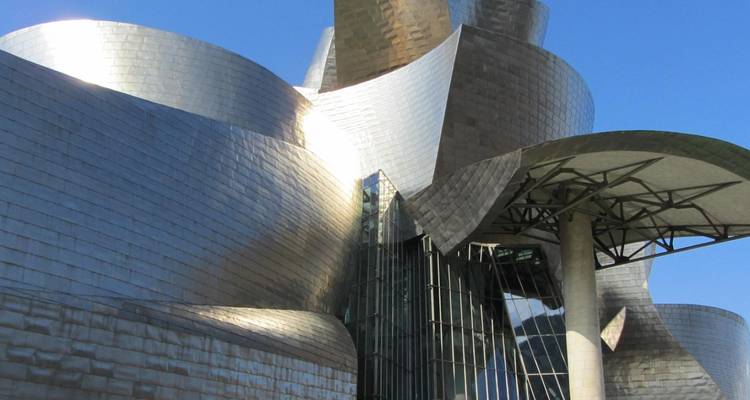 Architecture moderne aux courbes métalliques et surfaces réfléchissantes.