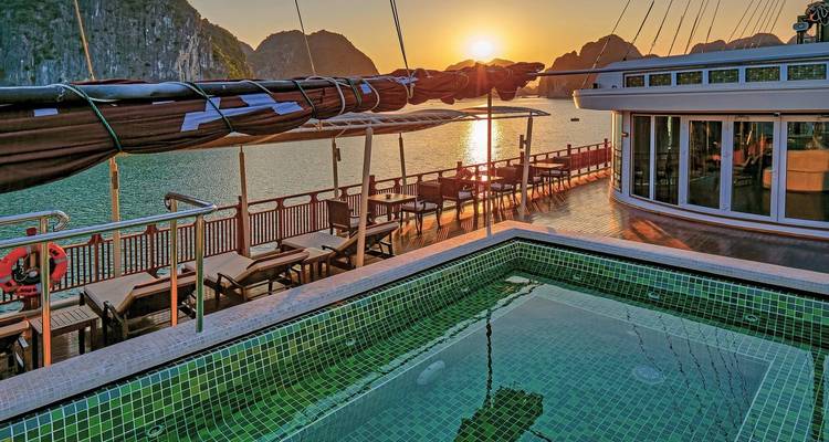 Deck eines Kreuzfahrtschiffs mit Swimmingpool mit Blick aufs Meer während des Sonnenuntergangs.