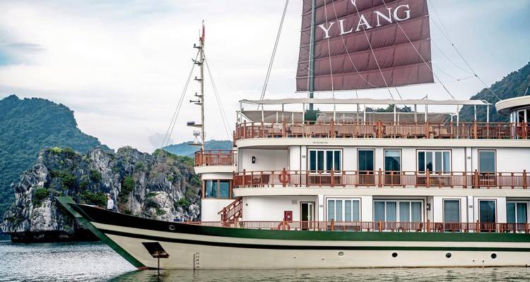 Seitenansicht eines großen Kreuzfahrtschiffs mit Segeln, umgeben von malerischer Landschaft.
