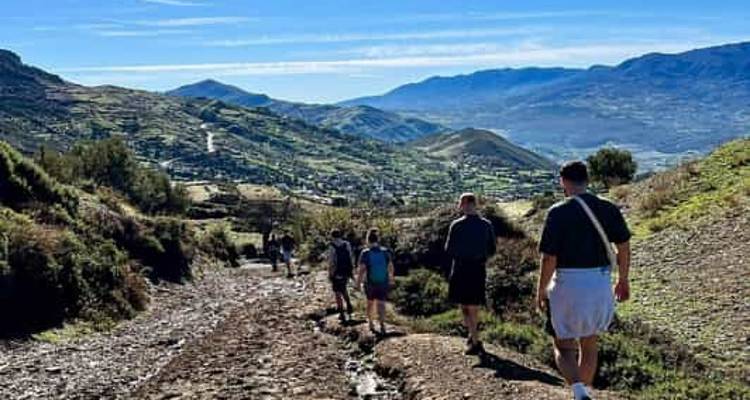 Group of people walking down a rural path with scenic valley views.