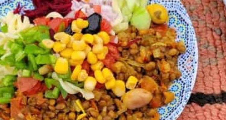 Plate of colorful vegetables and lentils served on a patterned dish.