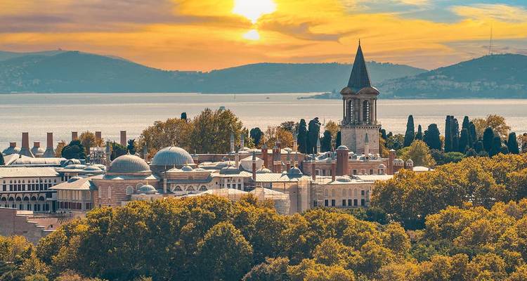 Vue panoramique d'une ville historique et monumentale au bord de l'eau au coucher du soleil.