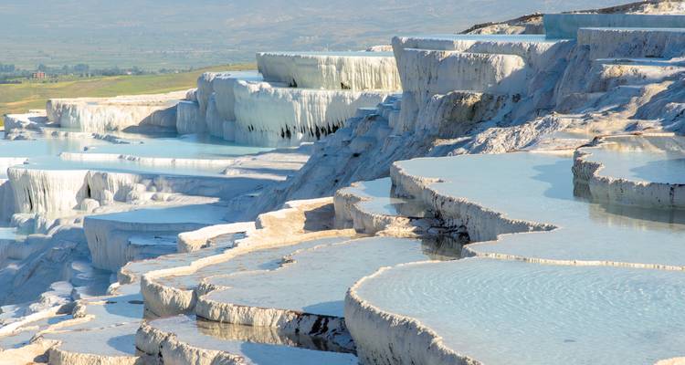 Side angle of stepped Pamukkale basins gleaming white against the landscape
