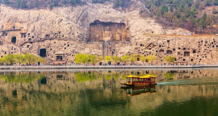 Longmen Grotten met een boot op de reflecterende rivier.
