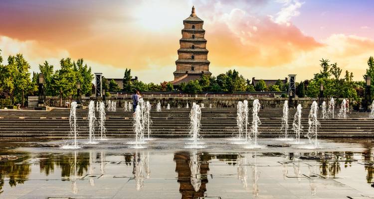 Pagoda met waterfontijnen op de voorgrond bij zonsondergang.