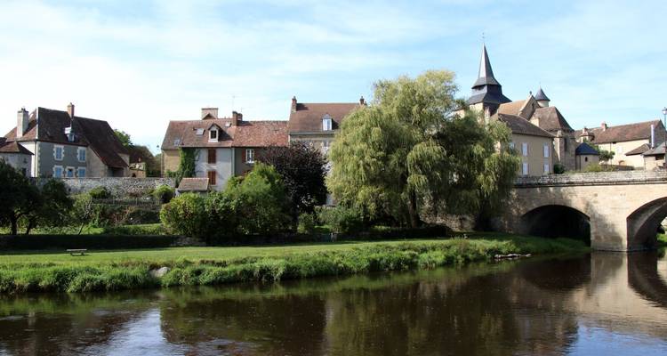 Charming town by a river with an arched stone bridge and old buildings.