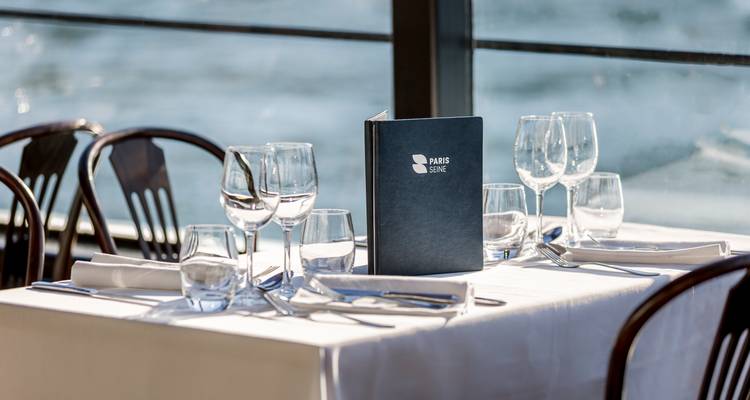 Configuration de table sur un bateau-restaurant parisien présentant un menu.
