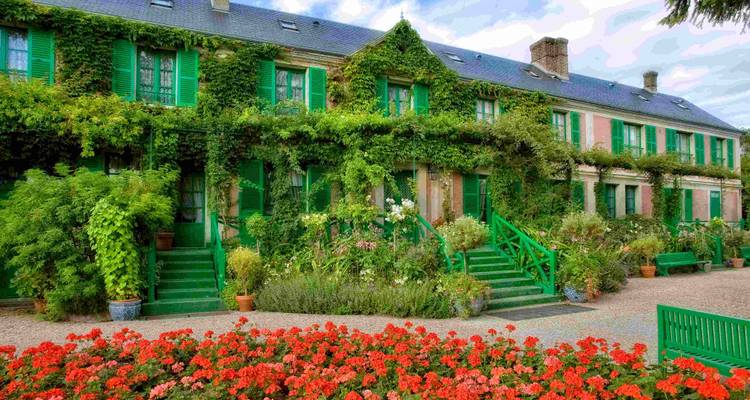Altes Haus mit grünem Efeu und roten Blumen in Monets Garten.