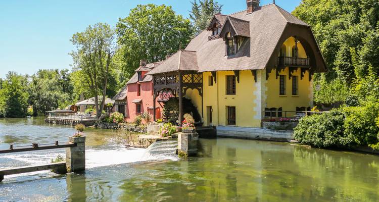 Maison pittoresque au bord d'un ruisseau dans un environnement verdoyant.