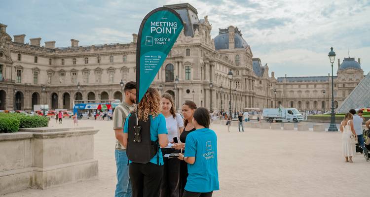 Eine kleine Reisegruppe versammelt sich an einem Treffpunkt mit Flagge vor dem Louvre-Palast.
