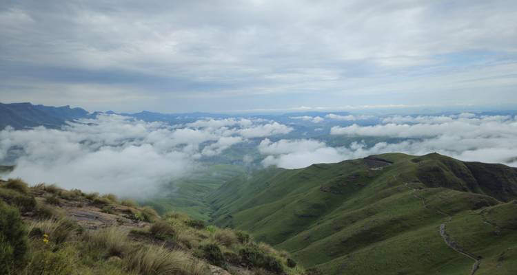 Vue panoramique de collines vertes et de nuages s'étendant au loin.