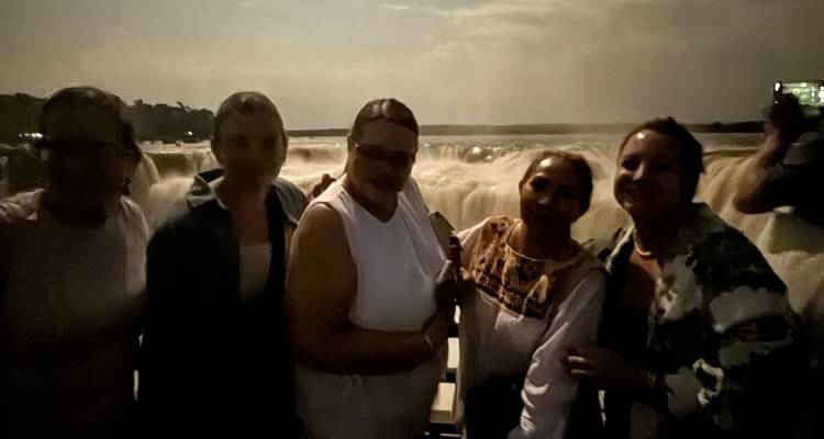 Groupe de personnes posant devant les chutes d'Iguazu la nuit.