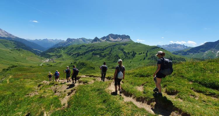 Groupe de randonneurs marchant le long d'un sentier de montagne avec des vues panoramiques.