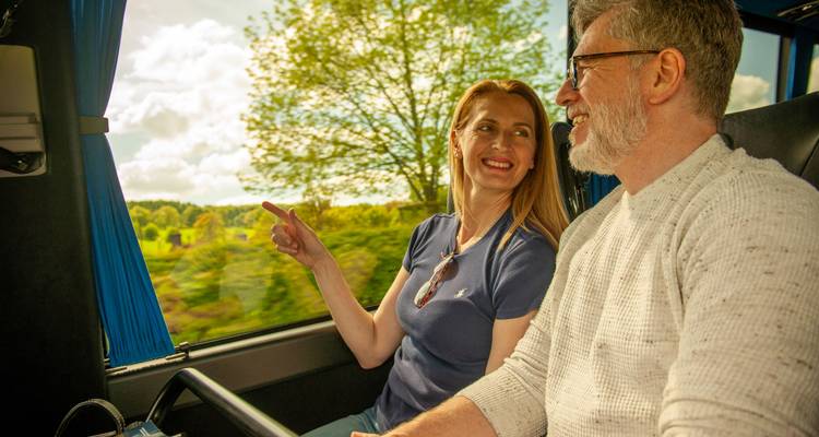 Couple sitting on a bus, enjoying a scenic view of nature outside the window.