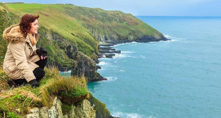 Persoon die geniet van een schilderachtig uitzicht op kliffen aan zee.