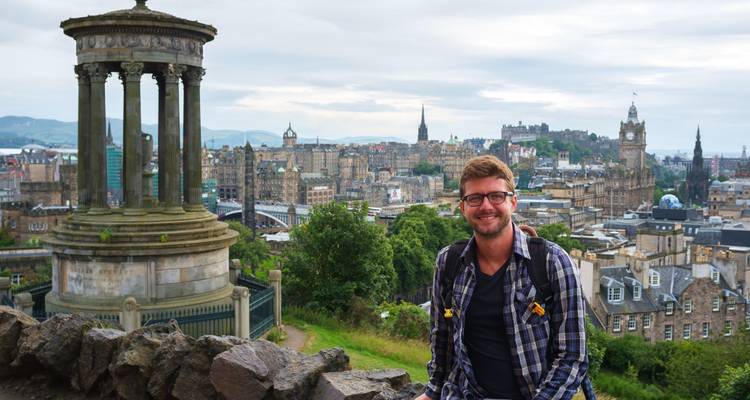 Persoon met stadsgezicht en monument op de achtergrond.