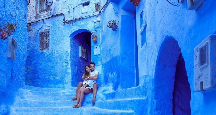 Couple assis sur des marches dans une ruelle d'un bleu éclatant.