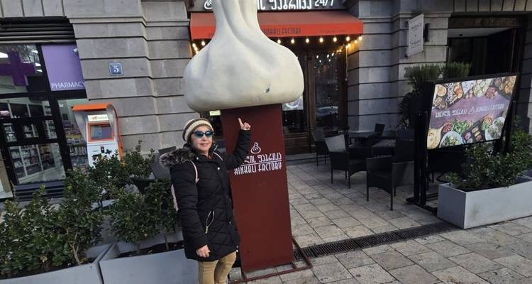 Femme pointant vers une grande sculpture d'ail devant un restaurant.