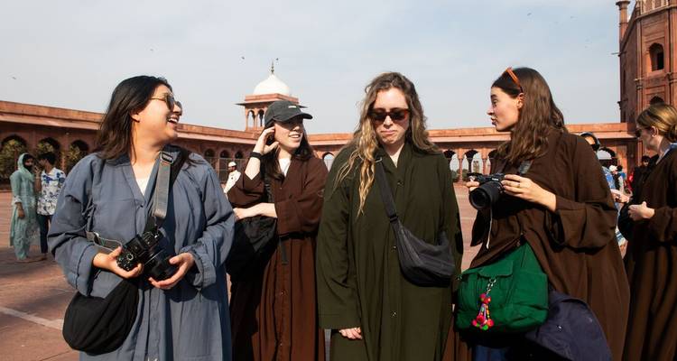 Groupe de touristes dans une mosquée historique portant des vêtements locaux.