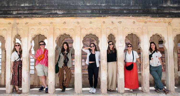 Des touristes qui posent devant un mur orné avec des fenêtres cintrées.