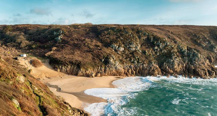 Secluded beach with cliffs and gentle waves.