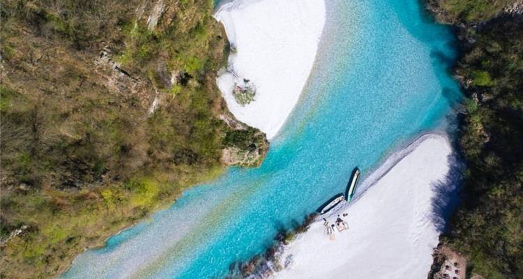 Aerial view of a river with boats and white sand.