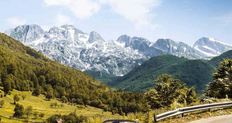 Mountain road with scenic valley and peaks in the background.