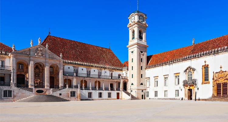 Eleganter Innenhof und Uhrenturm der Universität Coimbra unter einem strahlend blauen Himmel.