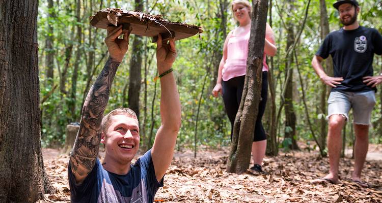 Drie mensen die glimlachen in een bosomgeving, mogelijk op een rondleiding.