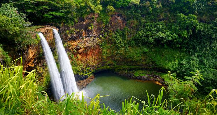 Waterfall cascading into a lush, forested basin.