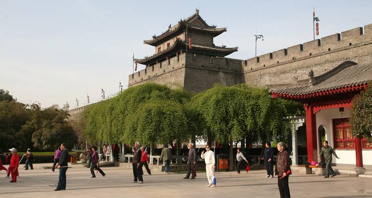 Here's the Dutch translation:

"Mensen die Tai Chi beoefenen bij een historische stadsmuur."