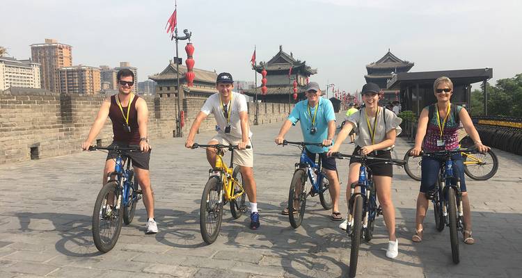 Groep fietsers op een historische stadsmuur.