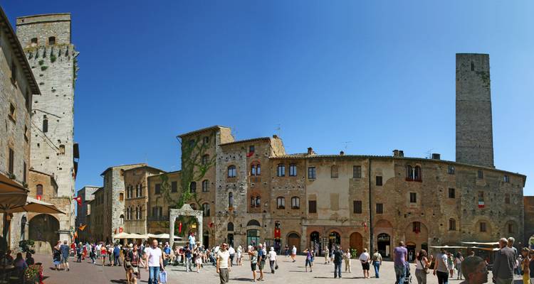 Place animée de San Gimignano avec des touristes et des bâtiments médiévaux.