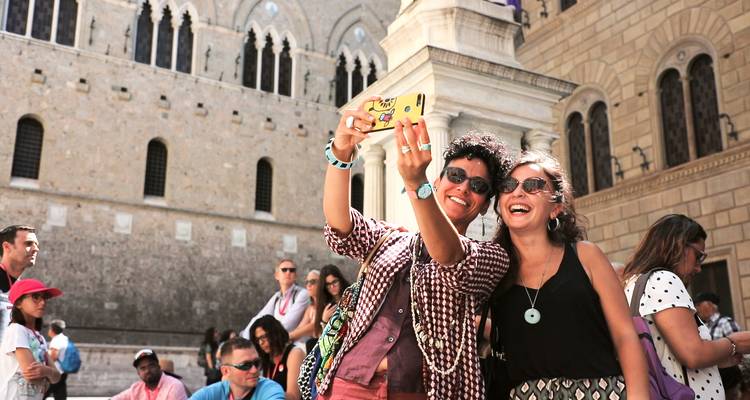 Deux touristes prenant un selfie devant un bâtiment historique.