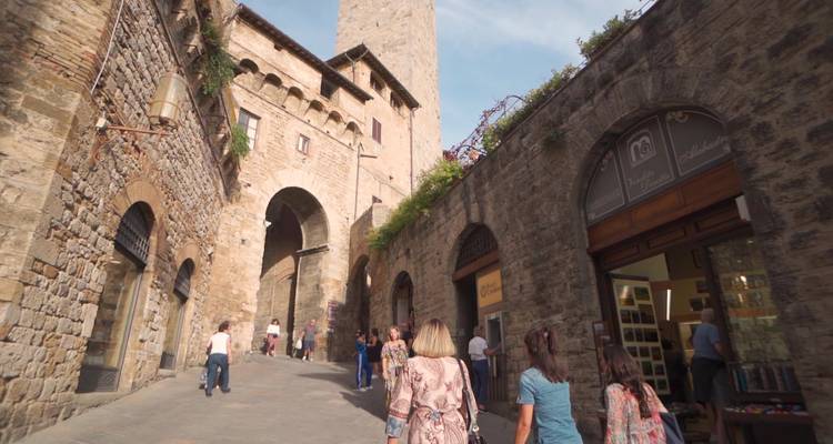 Mensen die door een historische stenen straat met winkels lopen.