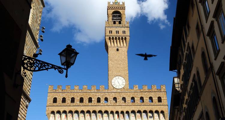 Palazzo Vecchio avec tour d'horloge et un oiseau qui passe en volant.