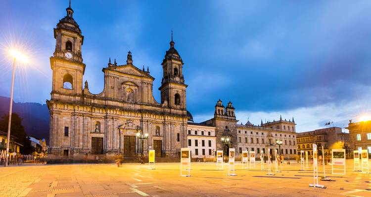 Plein met een grote kathedraal en historische gebouwen verlicht in de nacht.