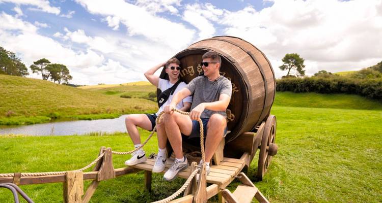 Los viajeros posan dentro de un enorme carrito de barril de madera en las verdes colinas de Hobbiton.