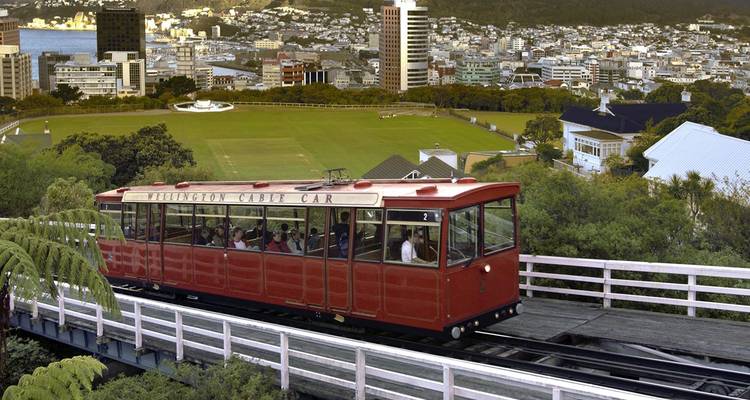 Teleférico Red Wellington subiendo por una ladera con los rascacielos de la ciudad y el puerto de fondo