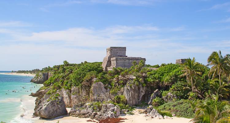 Ruinas mayas antiguas en un acantilado con vista a una playa.