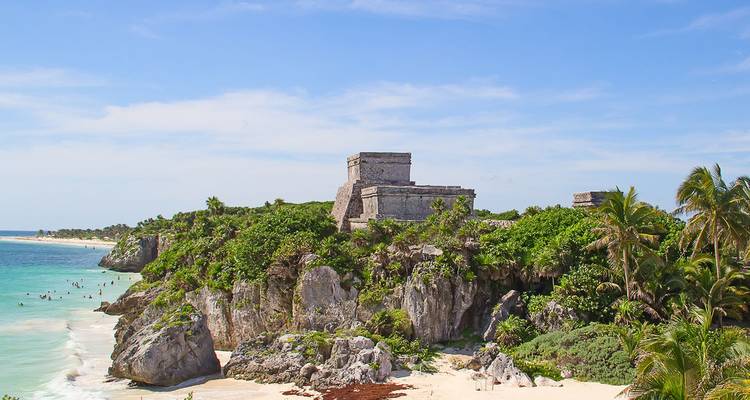Las antiguas ruinas del templo Maya de Tulum encaramadas en un acantilado sobre un mar turquesa brillante.