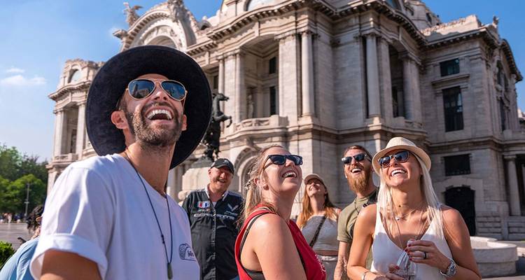 Los viajeros felices se ríen bajo la ornada fachada del Palacio de Bellas Artes en la Ciudad de México.