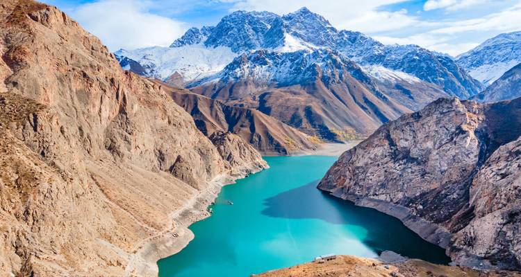 Turquoise lake surrounded by rocky mountains and snowy peaks.