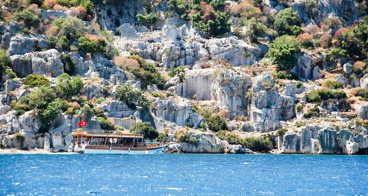 Boot op blauw water met rotsachtig landschap op de achtergrond.