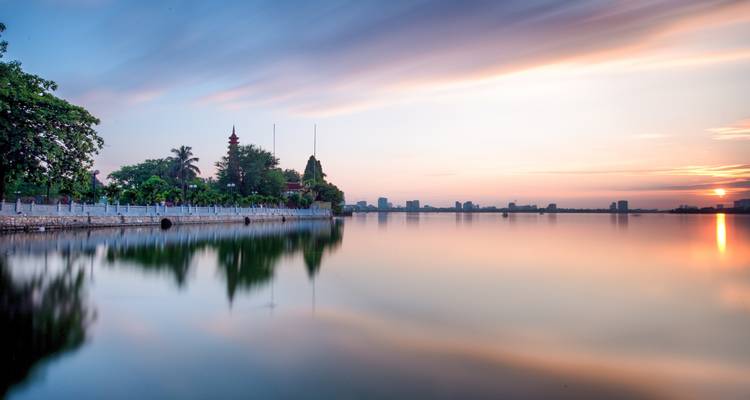 Vue panoramique d'un lac avec le reflet d'un temple et un coucher de soleil aux couleurs magnifiques.