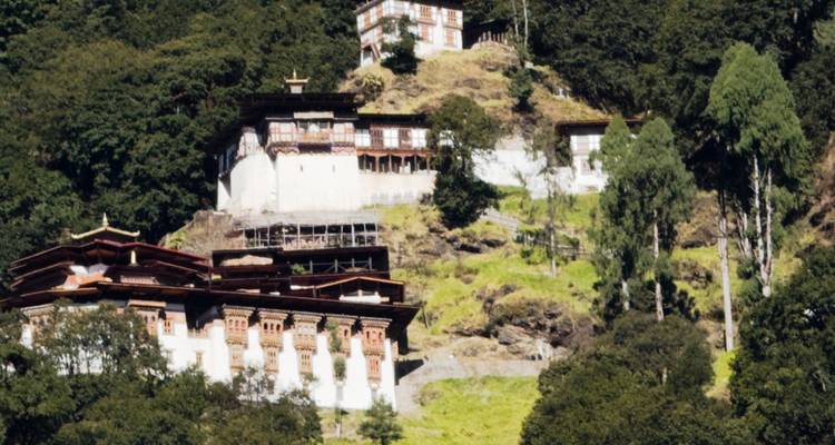 Plusieurs petits monastères blancs s'accrochent à une colline boisée escarpée au Bhoutan.